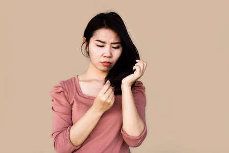 unhappy Asian woman hand holding her damaged split ends hairの写真素材