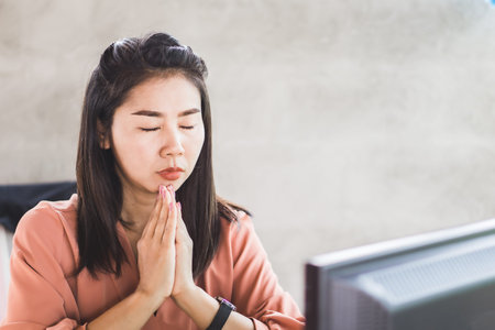 Asian business woman praying or do meditation at workplace ,sitting at office deskの写真素材