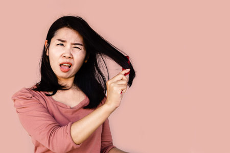 unhappy Asian woman using comp brushing her dry damaged long hair