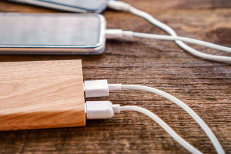 two smart phone charging with power bank on wooden tableの写真素材