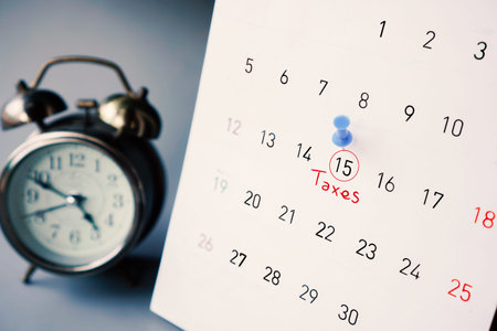 calendar showing pin on tax day with date 15th April with clock in background