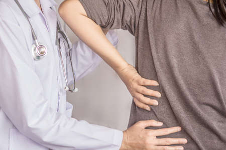 female doctor examining a patient suffering from back painの写真素材