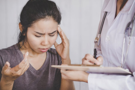 depressed Asian female patient talking to the doctor at a hospital explain her health problem