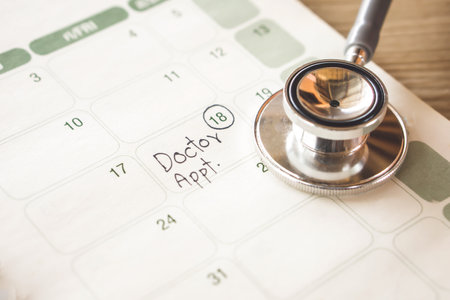 doctor appointment remind note on calendar and stethoscope on deskの写真素材