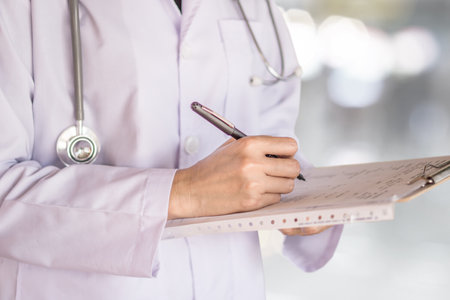 doctor with stethoscope on his neck writing prescription paper on clipboard
working at a hospitalの写真素材