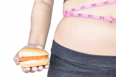 overweight woman with big belly hand holding burger ,unhealthy eating lifestyle isolated on white backgroundの写真素材