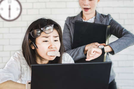 busy Asian female working hard under pressure from boss and deadline time, no time for lunchの写真素材