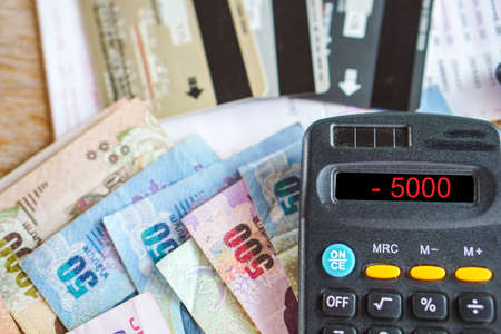 calculator with number in budget deficit for credit card debt payment with some banknotes on deskの写真素材