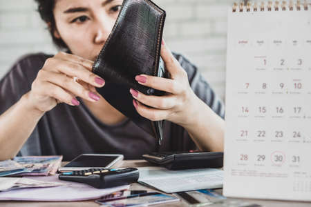 stress Asian woman open empty wallet looking for money for debt with bills, deadline calendar on deskの素材 [FY310160126955]