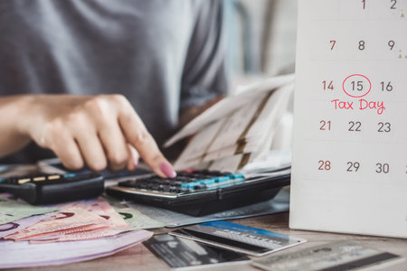 tax season concept with remind note on deadline calendar date 15th  with woman hand calculating in backgroundの写真素材