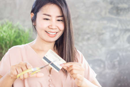 happy Asian woman hand cutting credit card by scissors with smiling face ,debt free conceptの写真素材