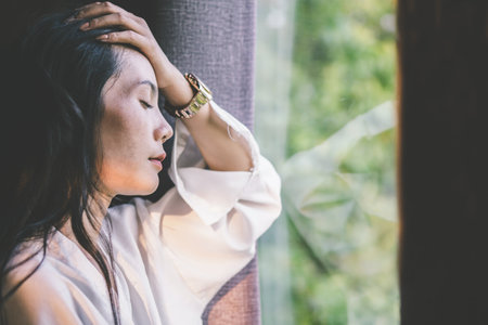 stress Asian woman having headache next to the window ,depression conceptの写真素材