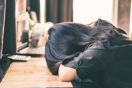 Depressed Asian woman sitting lonely in the room put the head down on the table