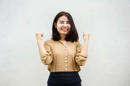 happy cheerful Asian business woman smiling over grey wall backgroundの写真素材