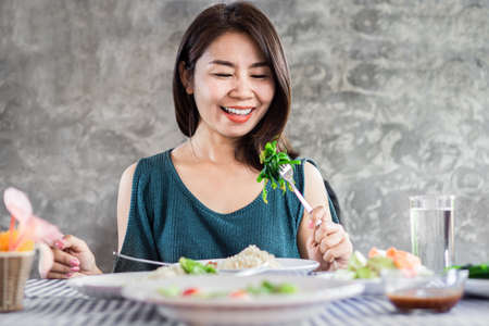 Happy Asian woman eating healthy food and green vegetablesの写真素材