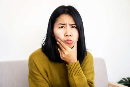 depressed Asian woman having problem with Bell's Palsy/Facial Palsy, hand holding her faceの写真素材