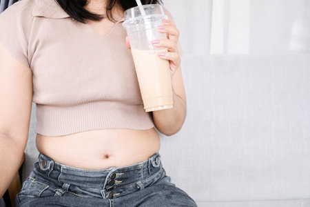 fat woman with big belly drinking  milk tea , sweet drink , sugar addiction conceptの写真素材