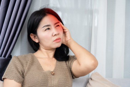 Asian woman having migraine headache feeling pain in one side of her headの写真素材