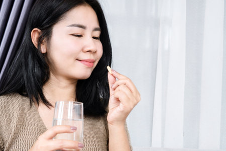 Asian woman taking vitamin c with a glass  of waterの写真素材