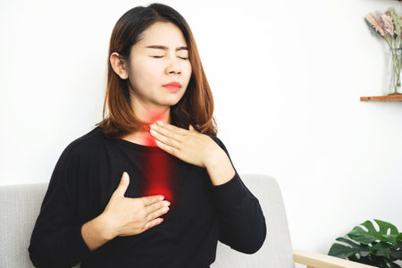 Asian woman suffering from acid reflux or gastroesophageal reflux disease (GERD) feeling uncomfortable and burning chest move up to neck and throatの写真素材
