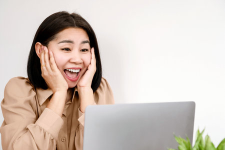 portrait of excited Asian business woman happy success at work looking at her job on laptop screen with smiling faceの写真素材