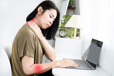 Cervical Radiculopathy (Pinched Nerve) concept with Asian woman suffering from neck and shoulder pain radiating down the arm from long-term computer useの写真素材