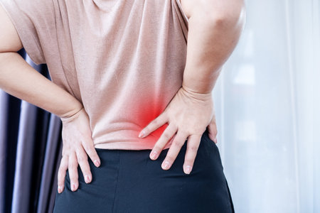 Closeup of a Woman with Lower Back Pain, Muscle Strain, and Spasms due to Prolonged Sitting and Poor...