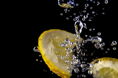 Sliced lemon in the water on black backgroundの写真素材