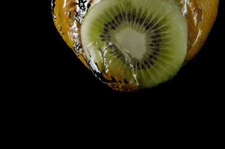 Kiwi fruit and orange in water on a black backgroundの写真素材