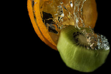 Kiwi fruit and orange in water on a black backgroundの写真素材