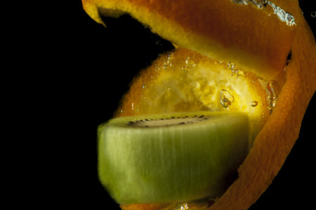 Kiwi fruit and orange in water on a black backgroundの写真素材