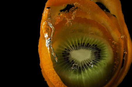 Kiwi fruit and orange in water on a black backgroundの写真素材