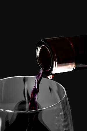Wine flow, glass and  bottle on a black backgroundの写真素材