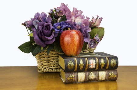 asorted flowers with books and a appleの写真素材