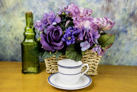assorted flowers with a tea cup and a green bottleの写真素材