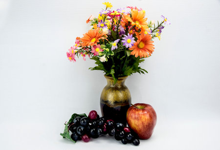 assorted flowers with a apple and grapes on a white back ground.の写真素材