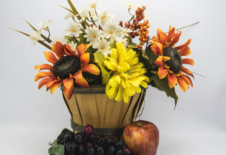 assorted flowers in an basket with a apple and grapes,の写真素材