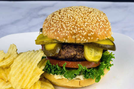 hamburger top with pickle  and served with potato chipsの写真素材