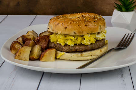 breakfast sandwich consisting of sausage patty and scrambled eggs  between an everything bagelの写真素材