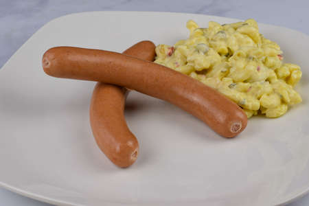 two hot dogs arranged on a plate with a side of macaroni saladの写真素材