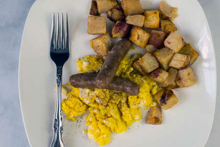 scrambled eggs top with black pepperwith breakfast sausage and home friesの写真素材