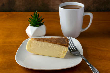 slice of cheese cake served with a cup of coffeeの写真素材