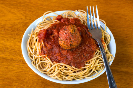 whole wheat spaghetti top with pasta sauce and plant based meat balls in a bowlの写真素材