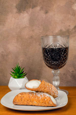 two cream filled cannolis  served with a glass of wineの写真素材