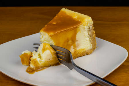 slice of cheese cake top with carmel and a forkの写真素材