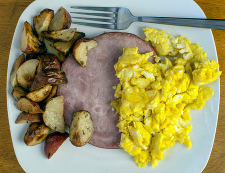 breakfast plate of scrambled eggs  ham and home friesの写真素材