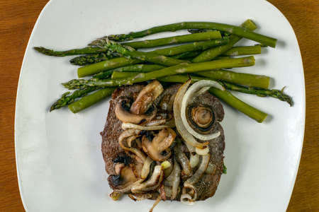 a steak sauteed with onions and mushrooms with asparagusの写真素材