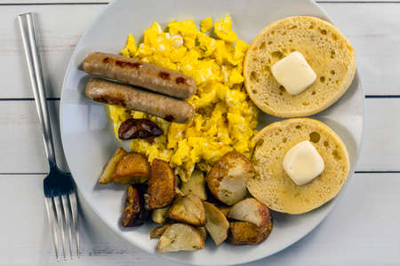 scrambled eggs served with sausage , homefries and english muffinsの写真素材