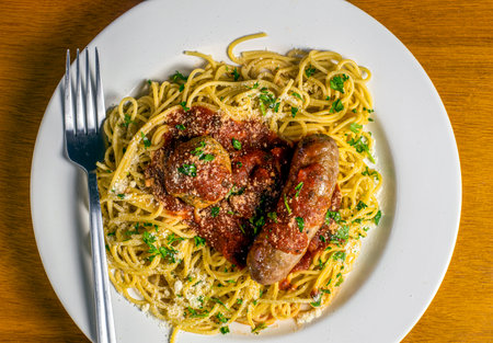 spaghetti top with  a meat ball and italian sausage covered in sauce.の写真素材