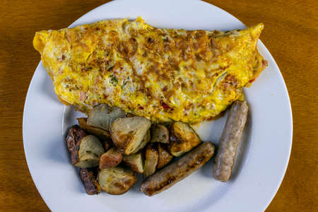 ham and pepper omlette served with breakfast sausage and red roasted potatoesの写真素材